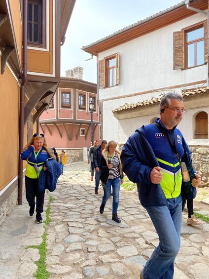 A cobblestone street with people walking, traditional buildings, and a clear sky. 5