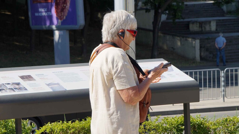 A person wearing headphones and reading a sign. 2