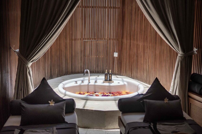 A spa area with a freestanding bathtub, two black cushioned chairs, and a wooden wall. 1