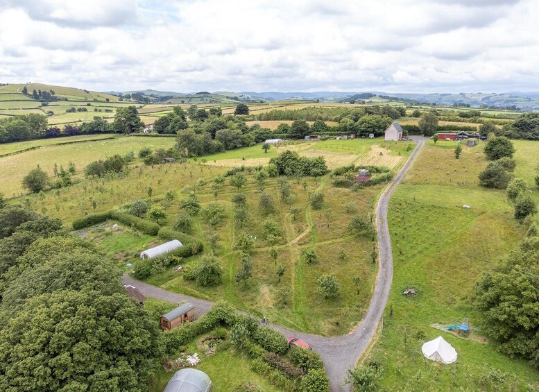 A rural landscape with rolling hills, fields, and scattered buildings. 4