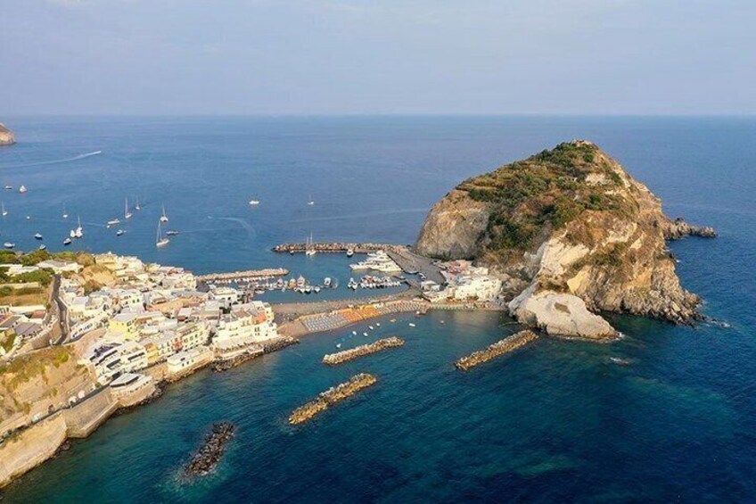 A coastal town with a rocky island, boats, and a marina. 3