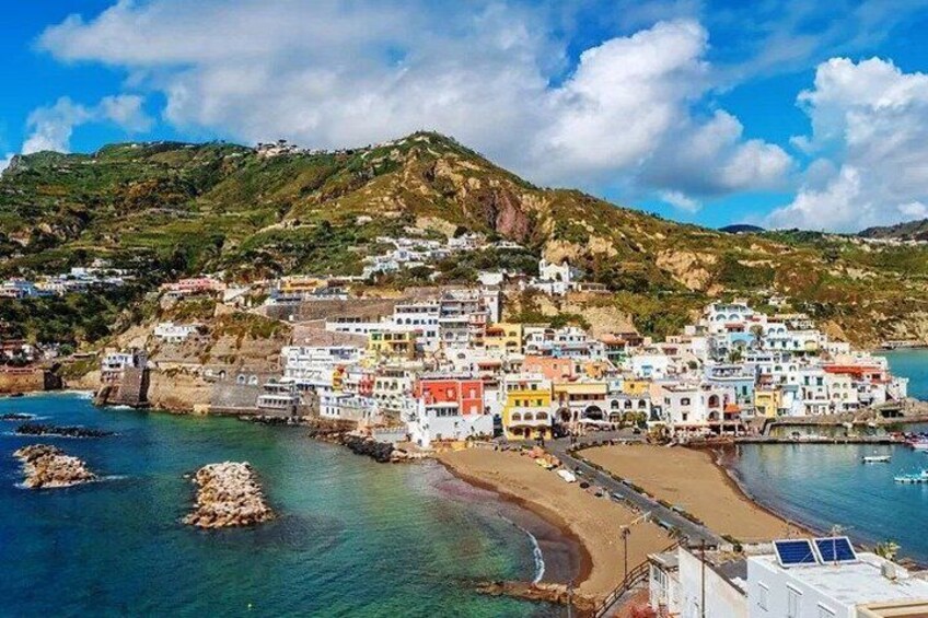 A coastal village with colorful buildings, a beach, and a rocky coastline. 4