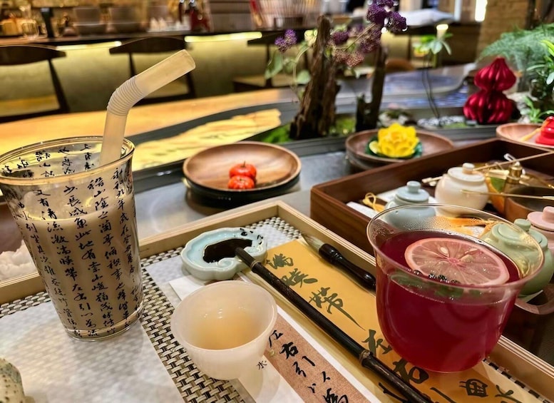 A traditional Japanese tea setting with a teapot, cups, and a drink with a slice of fruit. 1