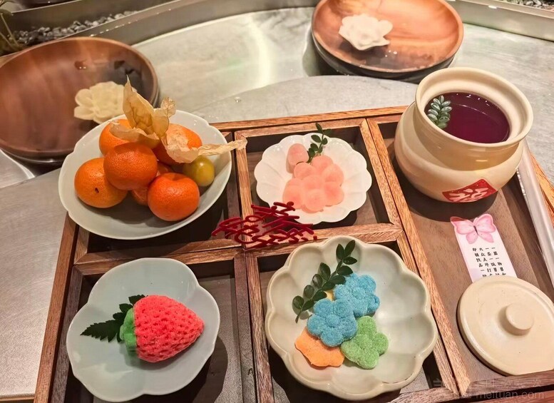 A tray with various food items, including oranges, a pink dessert, and a purple drink. 2