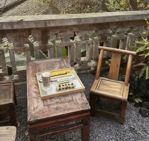 A wooden table with a tray of items, a wooden chair, and a stone balustrade in the background. 5