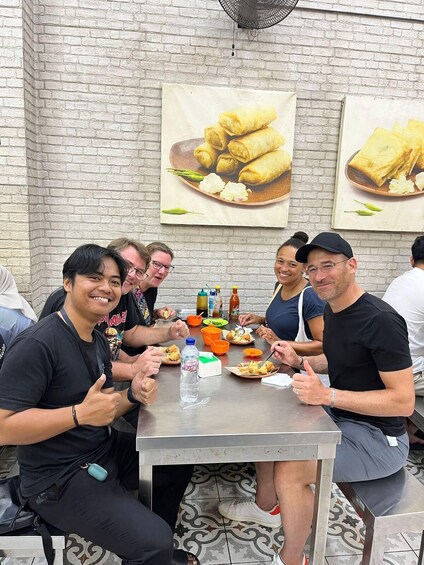 A group of people dining at a table with food and condiments. 1