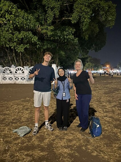 Three people posing in front of a white fence with trees in the background. 4
