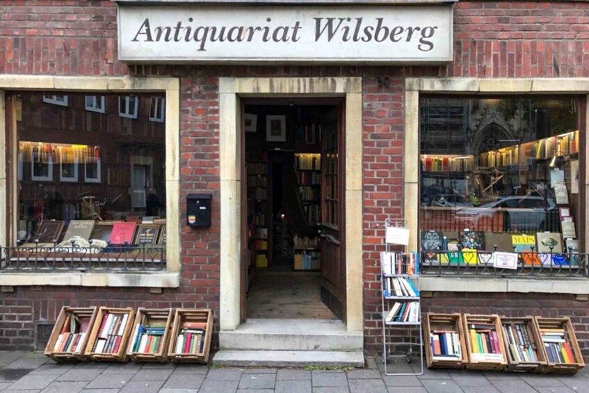 The storefront of Antiquariat Wilsberg with books displayed in windows and on the sidewalk. 3