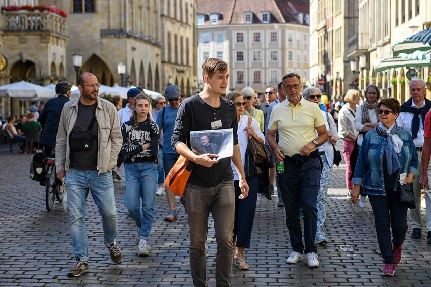A cobblestone street with pedestrians, historic buildings, and outdoor seating. 1