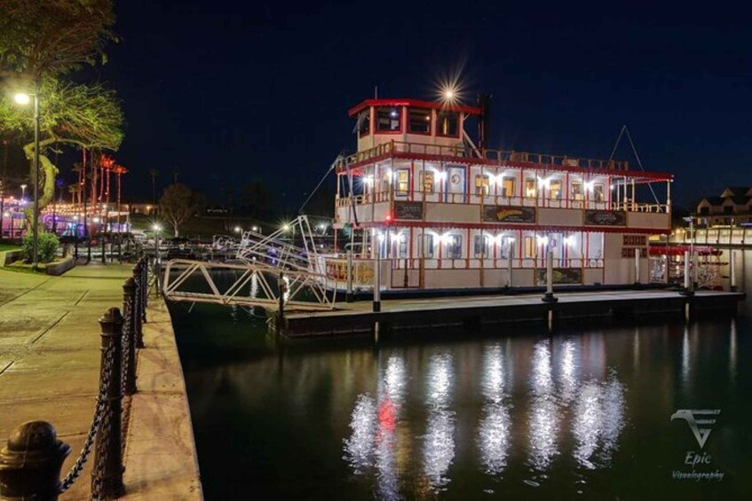 A brightly lit riverboat docked at a pier at night. 3