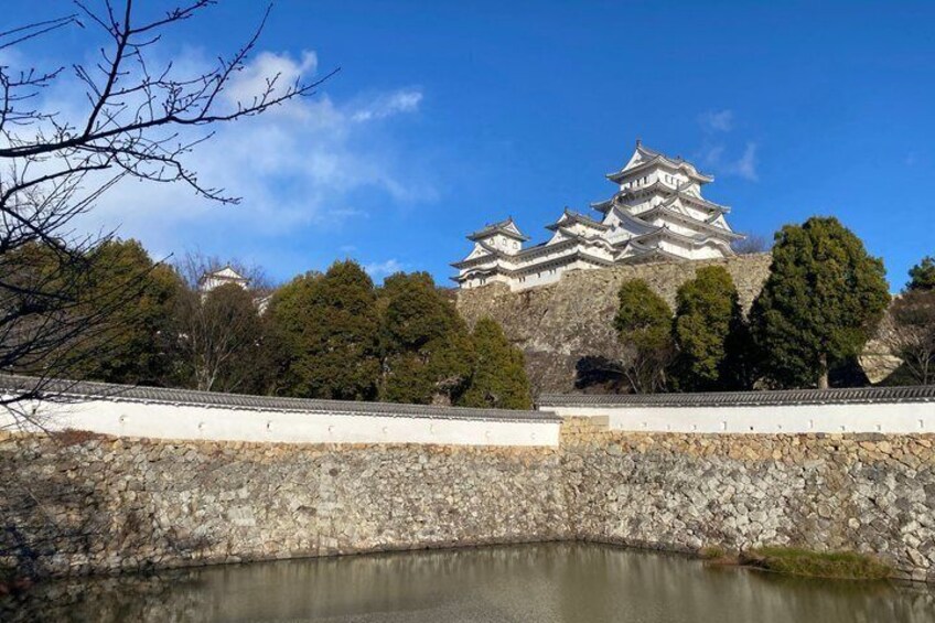 A traditional Japanese castle with multiple tiers, surrounded by trees and a stone wall. 3