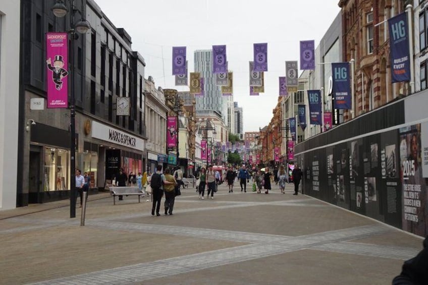 A busy urban street with pedestrians, storefronts, and hanging banners. 3