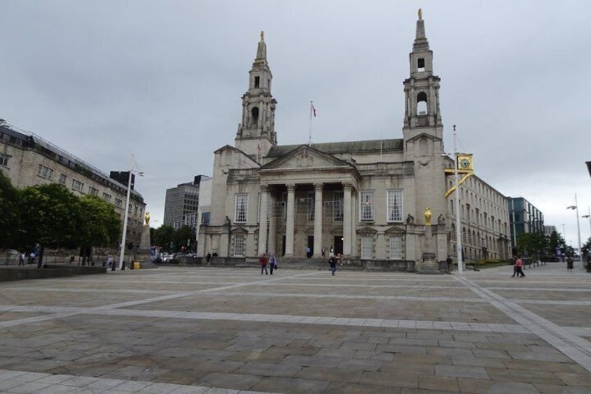 A large historic building with two towers, a central entrance, and a paved plaza. 5