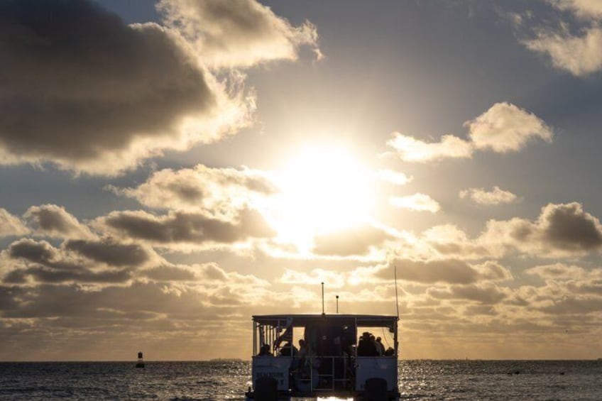 A boat with passengers on a body of water during sunset. 2