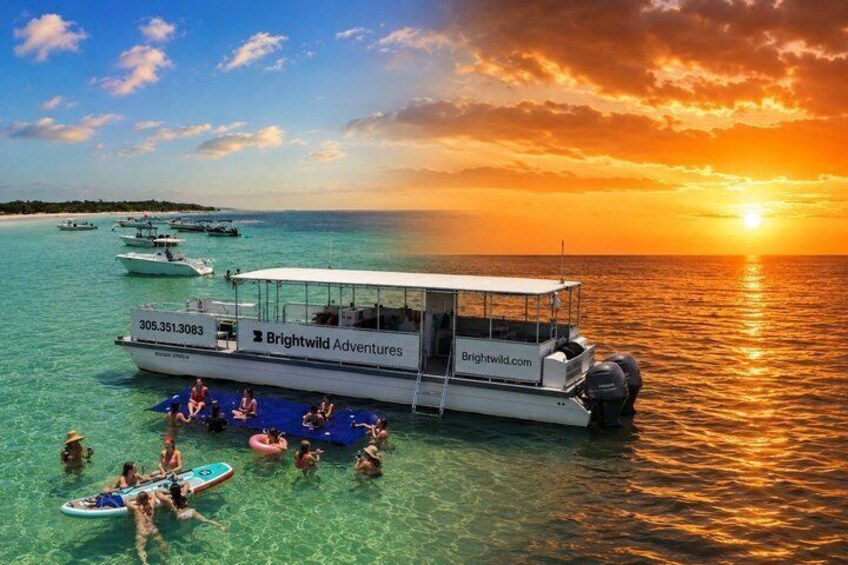 A boat with people on a clear day, surrounded by calm water and a sunset. 1