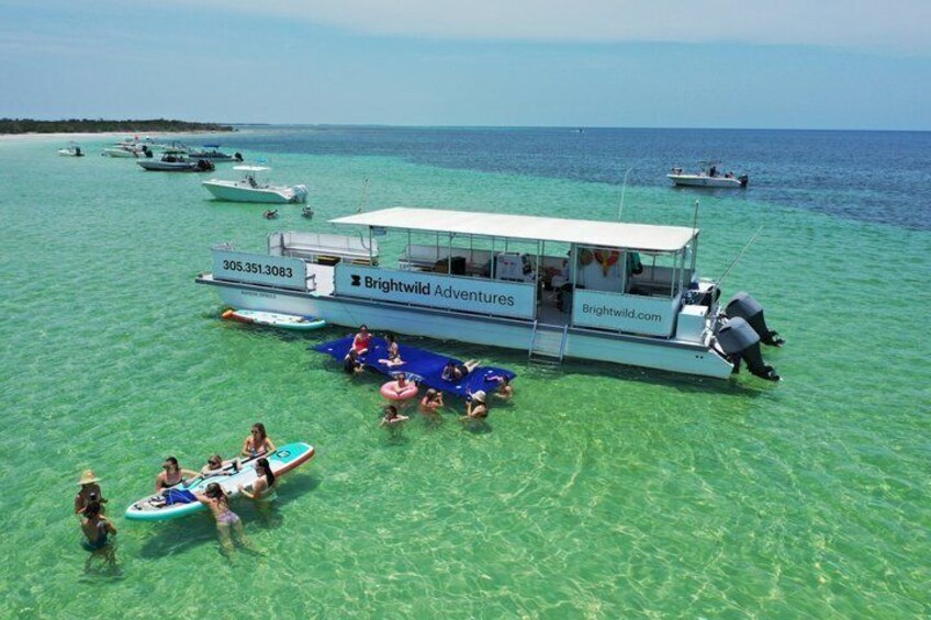 A boat with people on a clear blue sea, surrounded by other boats. 3