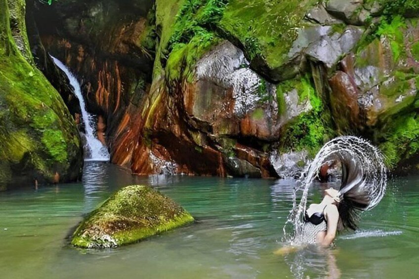 A waterfall, a person in water, and a moss-covered rock. 1