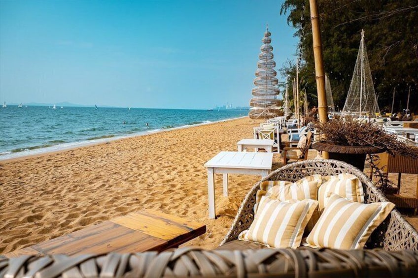 A beach with wicker furniture, a wooden table, and a hammock. 1