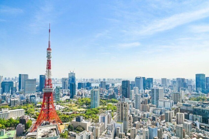 A cityscape with a prominent red tower, dense urban buildings, and a clear sky. 1