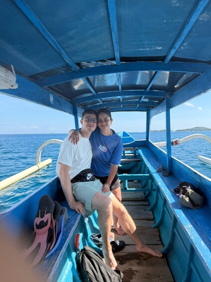 Two people on a boat with a blue interior, a clear sky, and calm sea. 5