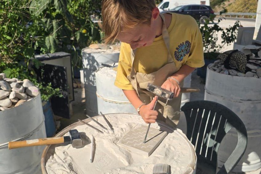 A person using a hammer on a stone block outdoors. 3