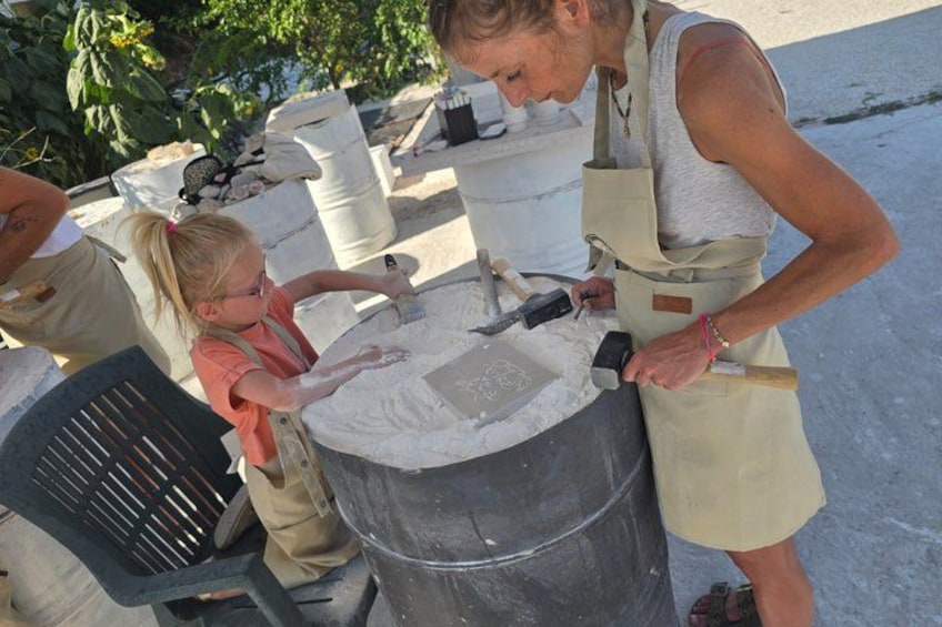 A person and a child mixing cement in a large container outdoors. 4