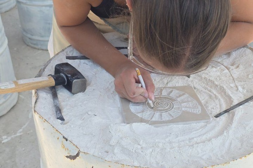 A person drawing a spiral design on a flat surface with a pencil. 1