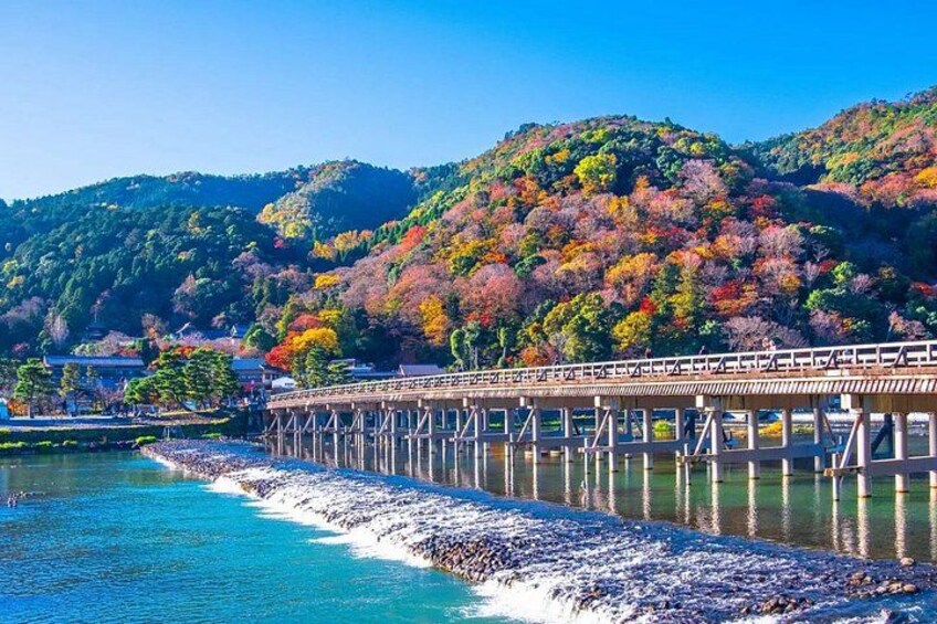 A wooden bridge over a river, surrounded by autumn-colored trees and hills. 5