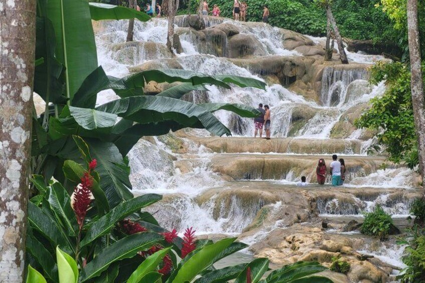 A waterfall with people standing on the rocks. 4
