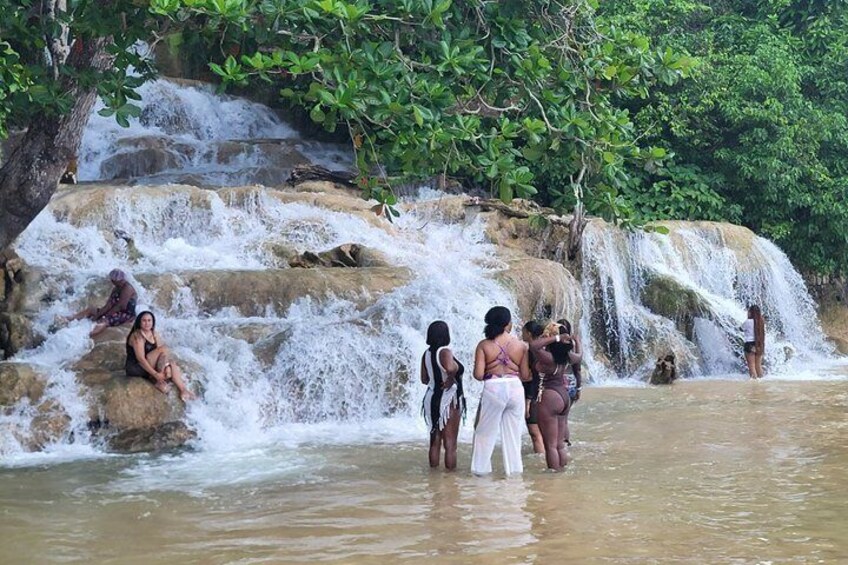 A waterfall, people sitting and standing by the water, and a rocky landscape. 5