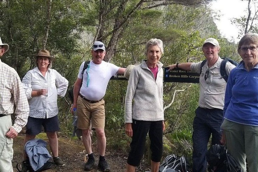 A group of people standing outdoors with a sign in the background. 5