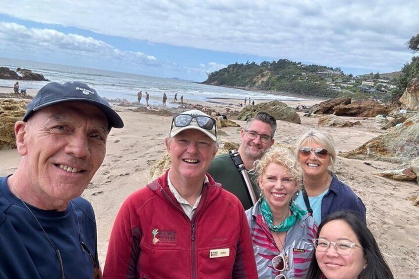 A group of people on a beach with rocky terrain and a view of the ocean. 2