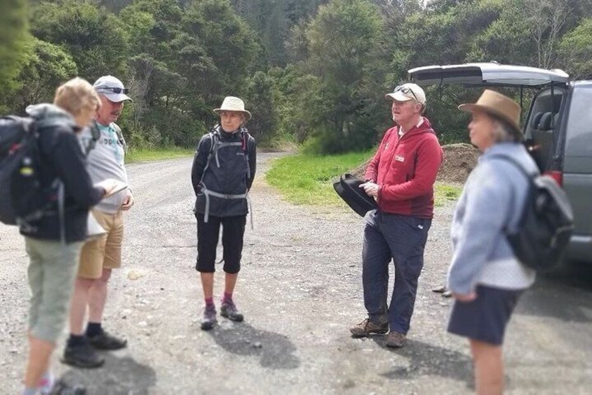A group of people standing on a dirt road with a forest in the background. 3