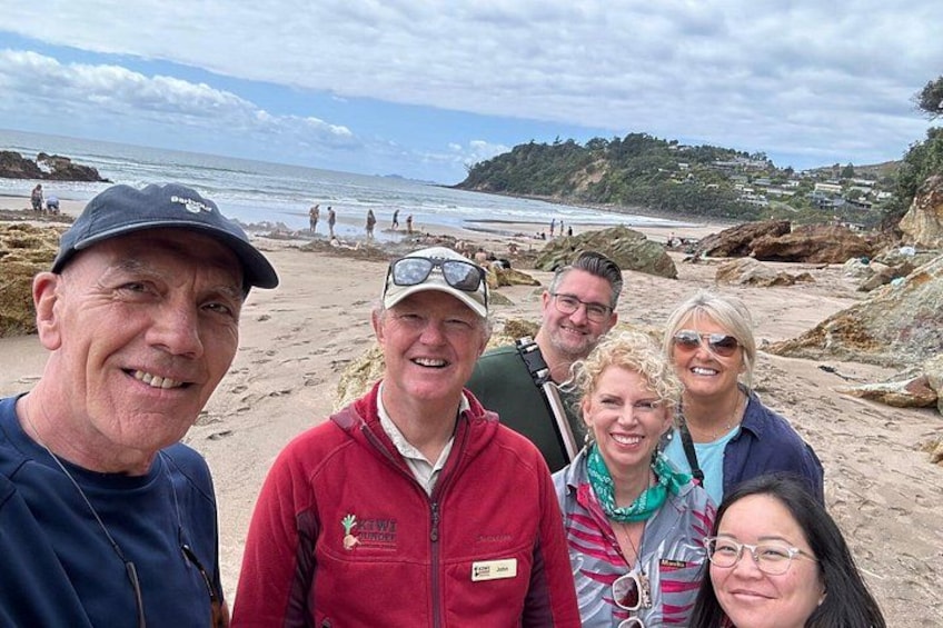 A group of people on a beach with rocky terrain and a view of the ocean. 3