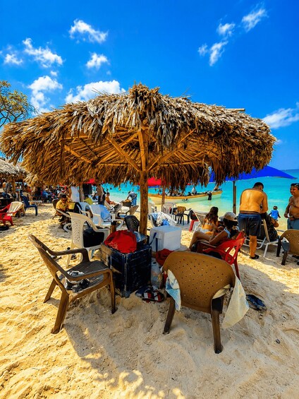 A beach with thatched umbrellas, sun loungers, and people relaxing. 1