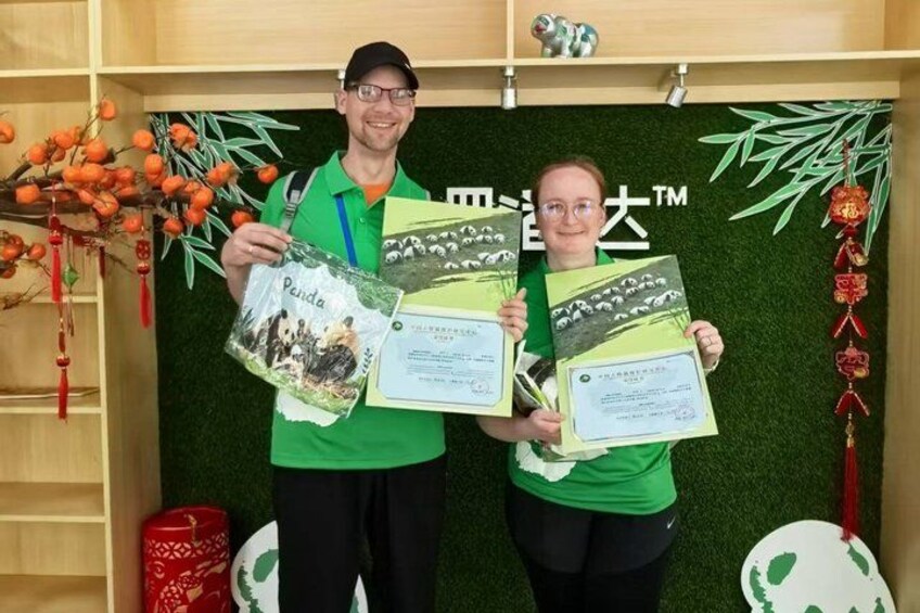 Two people holding certificates in front of a backdrop with a panda illustration and the text 'Panda'. 2