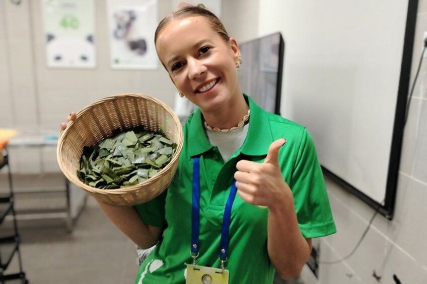 A person in a green uniform holding a basket of green leaves and giving a thumbs-up. 3