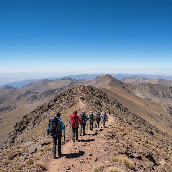 A group of hikers ascending a rocky mountain path with a clear blue sky above. 1
