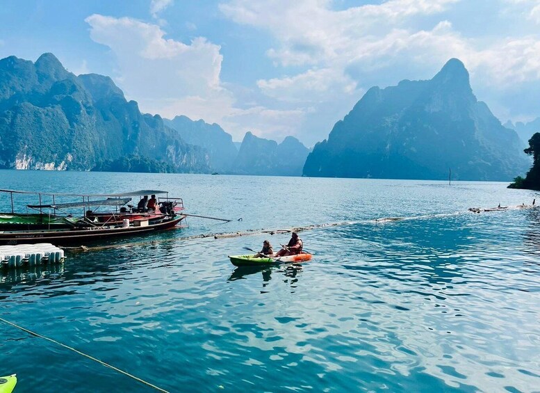 A calm lake with boats and kayaks, surrounded by mountainous terrain. 1