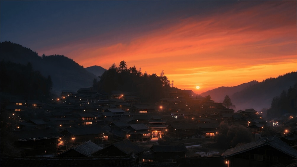 A village at dusk with a sunset, illuminated buildings, and mountains in the background. 3