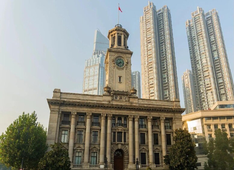 A historic building with a clock tower, surrounded by modern high-rise buildings. 4