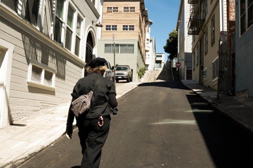 A person walking down a narrow street lined with buildings. 4
