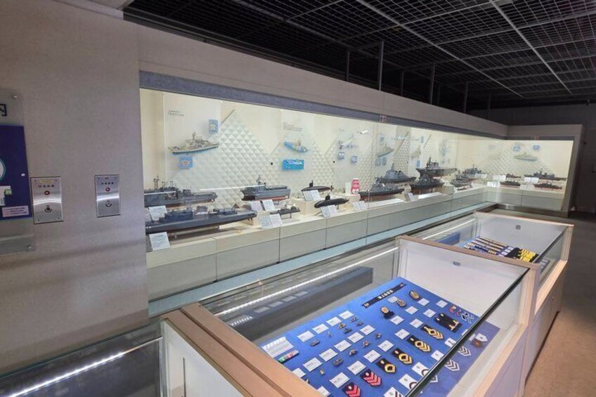 A museum exhibit with model ships and a display of medals. 3