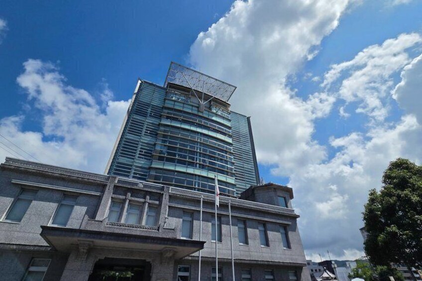 A modern skyscraper with a glass facade and a classical base, under a partly cloudy sky. 1