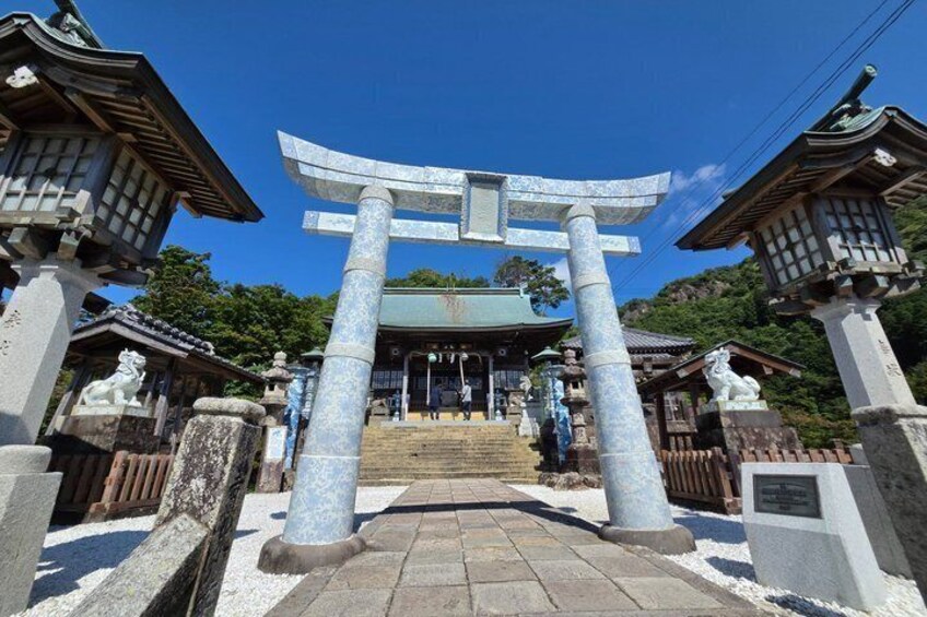 A traditional Japanese torii gate with a wooden structure and a stone base, leading to a shrine. 1