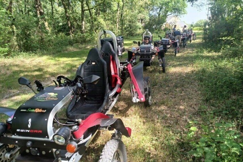 A group of off-road vehicles on a dirt path surrounded by greenery. 1