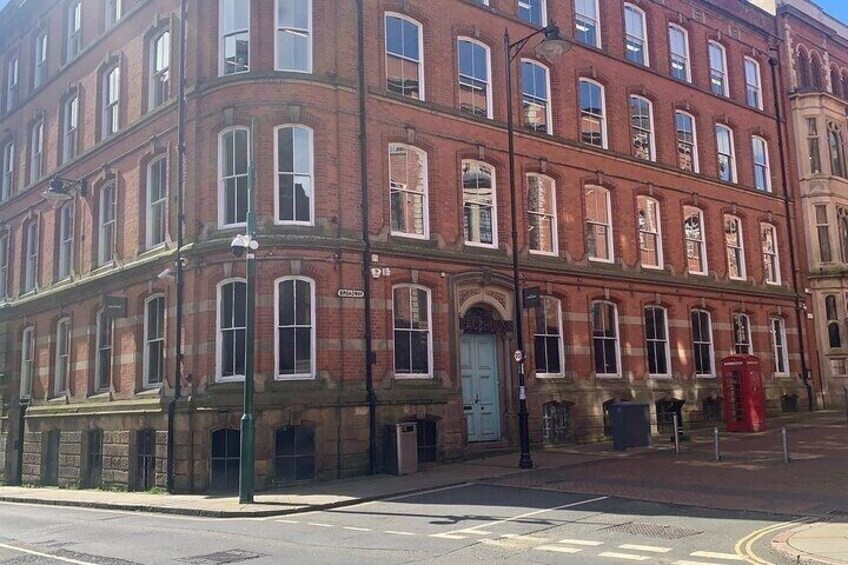 A red brick building with multiple windows and a blue door. 2