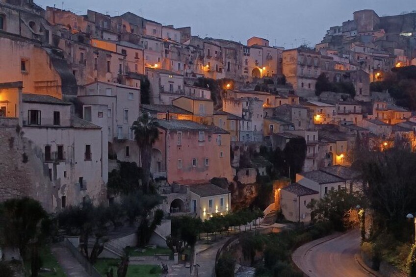 A densely packed hillside town with historic buildings, winding streets, and street lamps. 1