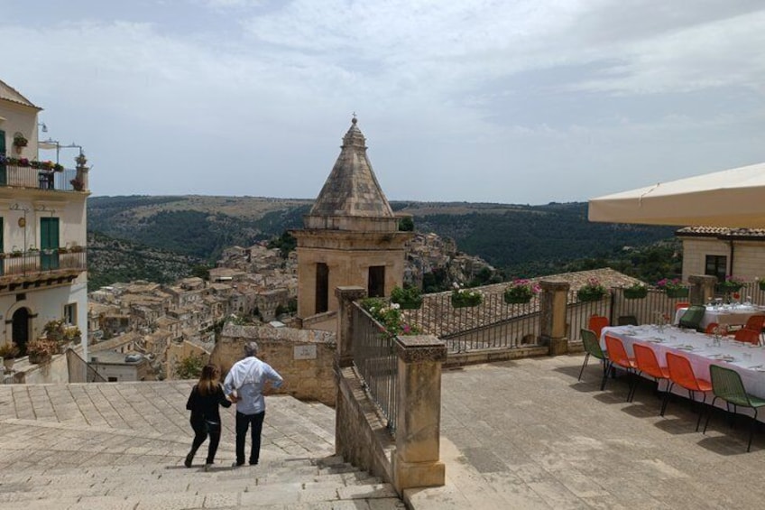 A historic town with stone buildings, a church, and a view of the countryside. 1