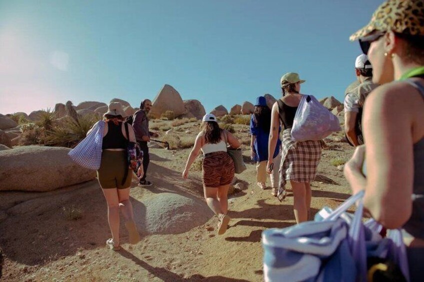 A group of people hiking on a rocky trail with large boulders and sparse vegetation. 1